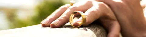 Closeup of the hand of a woman who has taken off her wedding ring and is balancing it with one finger
